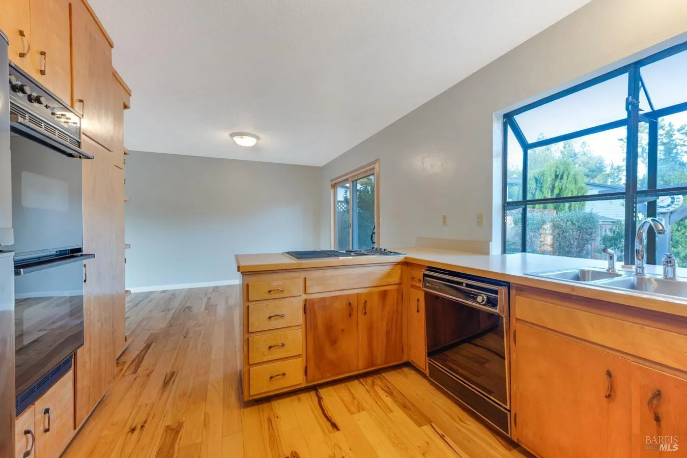 Kitchen cooktop peninsula, double ovens, and sink window