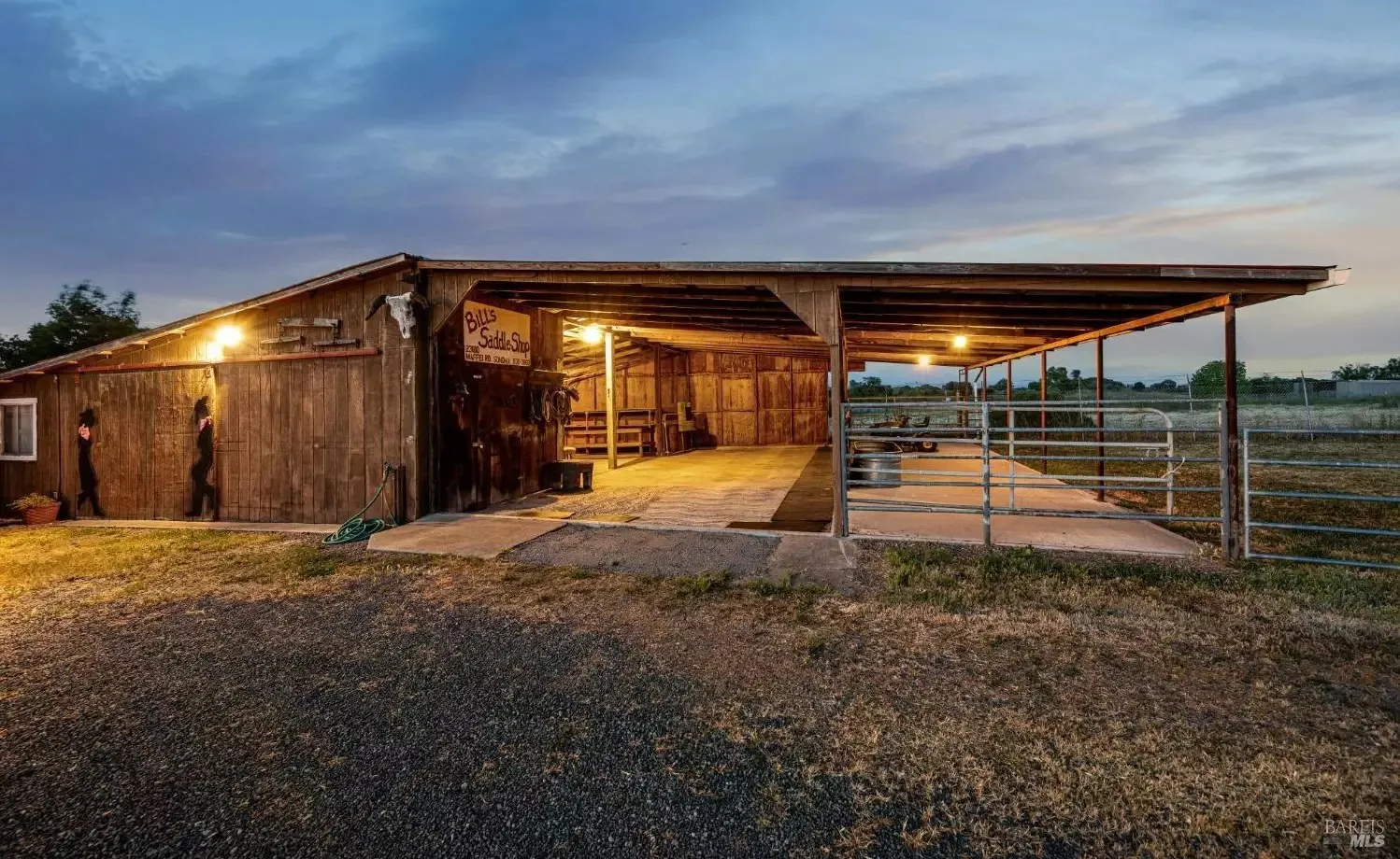 Barn and saddle shop with paddock fencing at dusk